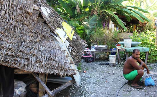 A Kiribati man outside his home after a king tide had swept through. Image: Kiribati Independent