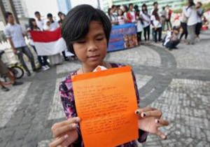  A street child reads a letter she wrote at 'Stop Violence Against Children', an event marking National Children's Day. Photo: Jakarta Globe