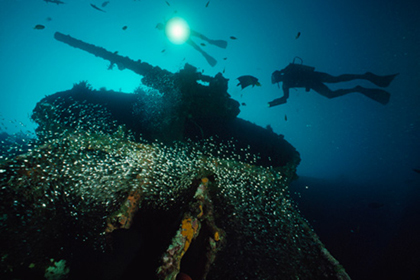 Divers in the Pacific explore the USS President Coolidge's forward gun turret. Photo: National Geographic