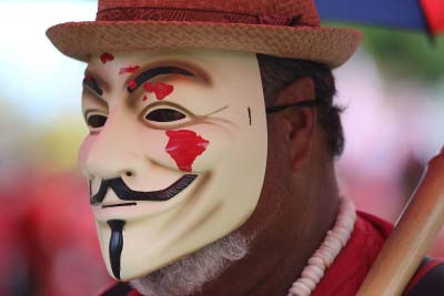 A masked Aloha Aina Unity March demonstrator. Image: cory Lum/ HCB